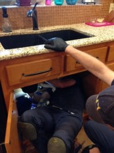 2 HEB plumbers work under a Hurst area kitchen sink