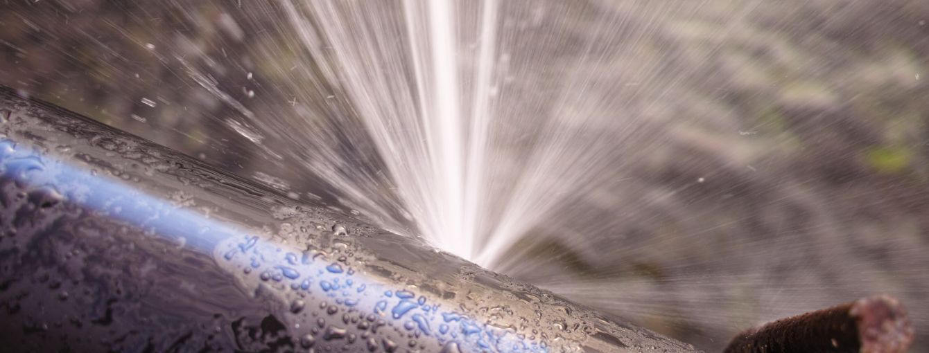 A pipe that has burst with water coming out.